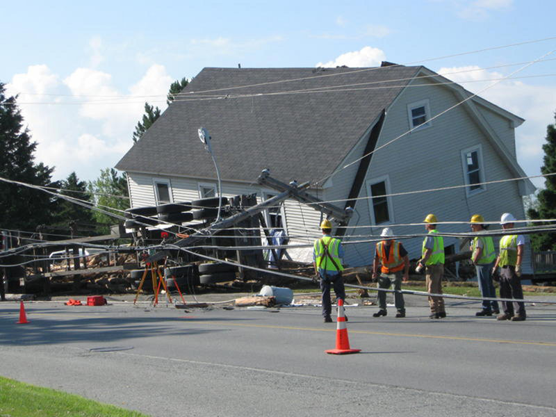 A logging truck rests on its side along Route 201 in Jackman, next to the home damaged by the logs that rolled off the truck’s bed. Authorities said the truck was driving through Jackman near the Canadian border around 2:30 a.m. when it struck telephone poles and rolled on its side, spilling its cargo. A 5-year-old boy sleeping inside the house was killed.
