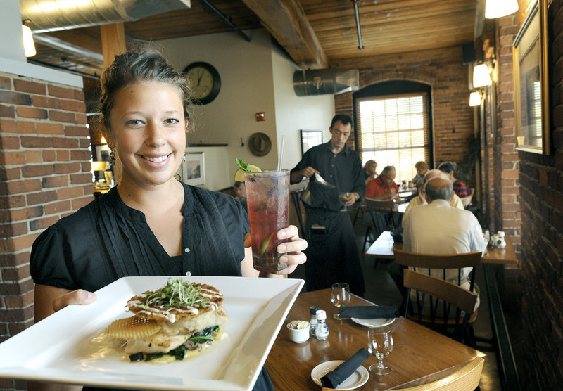 Caitlin Anthoine serves fish and chips with a Cold River blueberry mojito at Fish Bones American Grill, which overlooks a canal from the revitalized Bates Mill #6 in Lewiston.