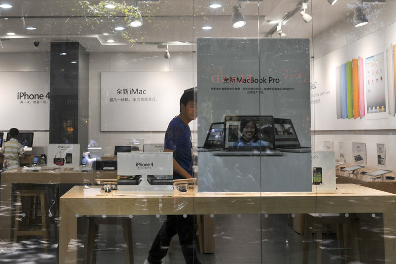A man dressed as an Apple store employee looks out from a window of a shop masquerading as a bona fide Apple store in downtown Kunming, in southwest China’s Yunnan province, Thursday. A store visitor said “some things were just not right.”