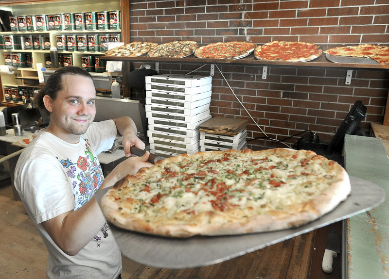 Nemo Burian hoists a freshly baked potato, bacon and scallion pizza at Otto Pizza on Congress Street in Portland, the Readers Choice winner for best pizza.