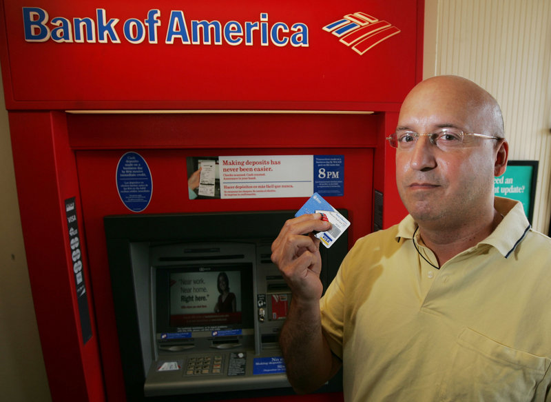 Scott Rozman holds up his Bank of America ATM card in Guttenberg, N.J. He says he plans to switch banks because of Bank of America’s fees.