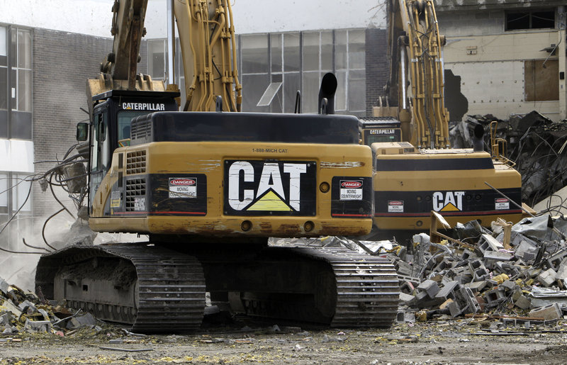 Caterpillar excavators tear down a school in Detroit. Demand for heavy equipment boosted quarterly profits 44 percent.