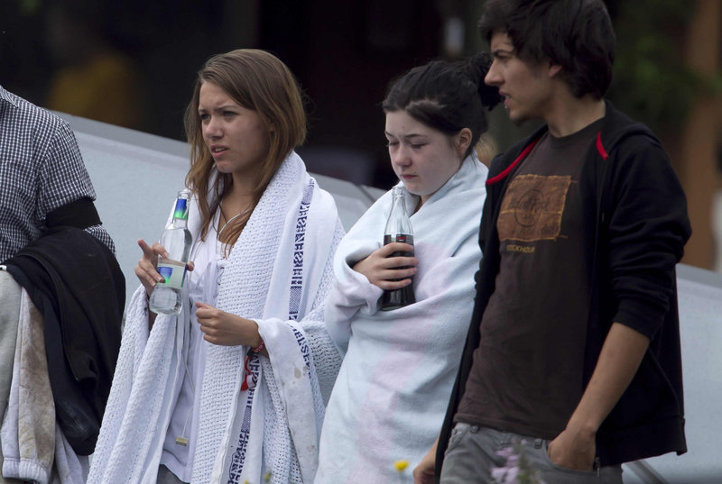 Unidentified survivors from the shooting at an island youth retreat stand wrapped in blankets outside a hotel where survivors were being reunited with their families in Sundvolden, Norway, on Saturday.