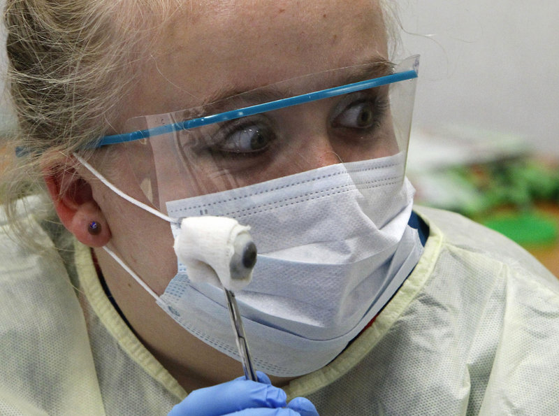 Lark Nash, 14, holds up a donated human eye so her lab partner can take a picture during a medical camp session for young students at Fauquier Hospital in Warrenton, Va.