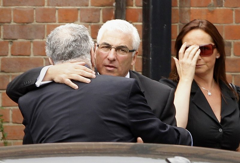 Mitch Winehouse, center, the father of deceased singer Amy Winehouse, is consoled as he arrives at a crematorium in north London on Tuesday.