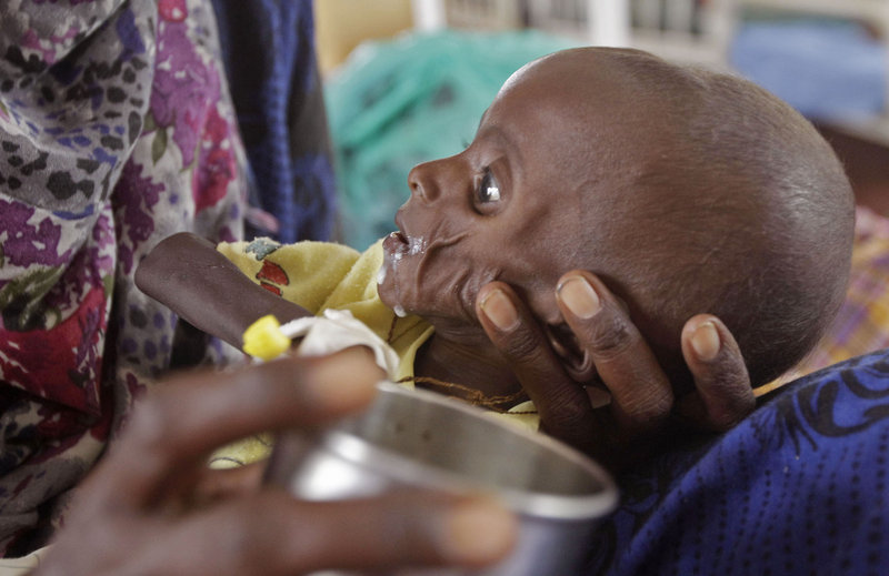 Mihag Gedi Farah, a 7-month-old Somali child who is severely underweight, is fed by his mother as he lies in a field hospital of the International Rescue Committee in the town of Dadaab, Kenya, on Tuesday. Tens of thousands of Somalis are fleeing to Kenya and Ethiopia, hoping to find aid in refugee camps.