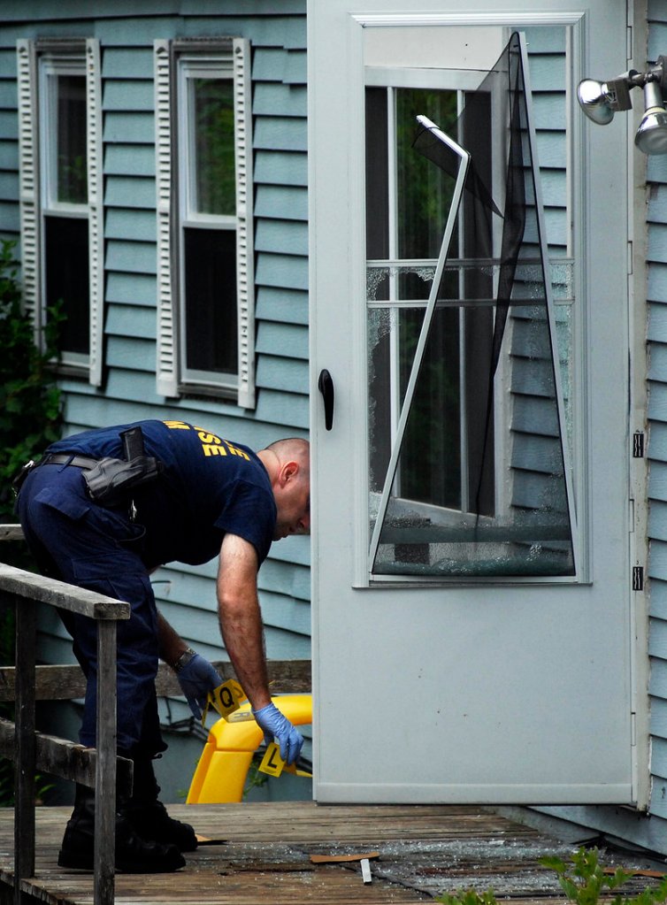 A member of the Maine State Police Evidence Response Team, right, collects markers Tuesday outside the mobile home at 322 Bennett Road.