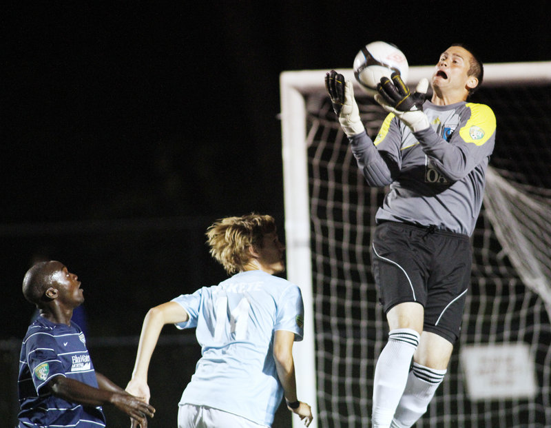 Portland goalie Matt Williams makes a save as teammate Brian Fekete, center, holds off a New Hampshire player Tuesday night during a Premier Development League playoff game at Deering High. New Hampshire advanced with a 1-0 victory.