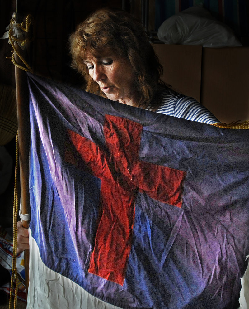 Deb Baker holds a Christian flag that she said had been hanging in the back of the Raymond Hill Baptist Church since she was a child. Baker, who lives less than a half-mile away, retrieved the flag Tuesday night after a fire severely damaged the building.