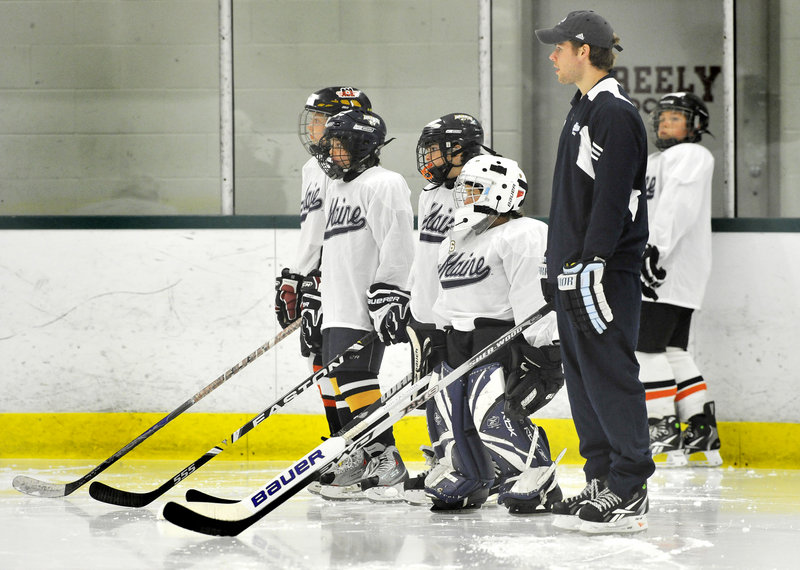 Will O' Neill, a captain on the University of Maine hockey team, listens to instructions before conducting a drill with youngsters at the Black Bear Hockey Camp at Falmouth Ice Center.