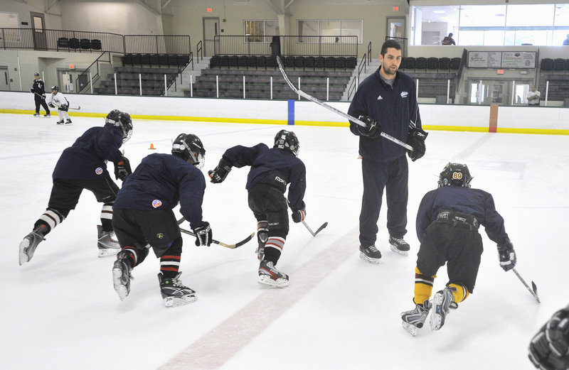 Matt Duffy, a former University of Maine hockey player from Windham, leads a group of young players through a drill Wednesday during a summer hockey camp at Falmouth Ice Center. Twelve current and former UMaine players are working at the camp this week.