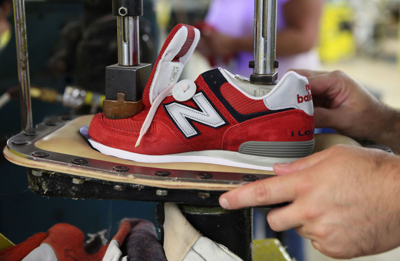 A worker uses a press to attach a shoe upper to the outsole at the New Balance factory in Norridgewock. Since 2004, the 350 workers at the plant have increased daily production by nearly 9 percent.