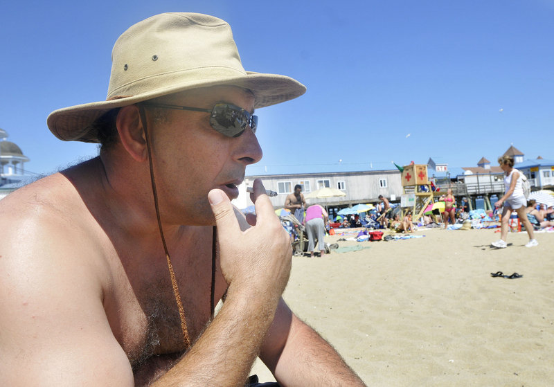 Visiting from Canada, Ali Guvenc smokes in Old Orchard Beach on Thursday. Responding to a proposed ban on smoking on the town’s public beaches, he questioned how the government can justify further restricting an activity that is legal for those 18 and older.