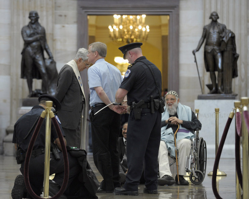 Rabbi Arthur Waskow, seated, waits to be arrested by Capitol Police in the Rotunda of Capitol Hill in Washington on Thursday. Rep. Chellie Pingree, D-Maine, defended members of the group of civic and religious leaders who were arrested after protesting proposed budget cuts associated with debt ceiling negotiations.