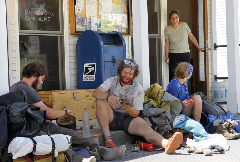 Postmistress Maie Beane chats with Appalachian Trail thru-hikers, from left, Greg Brown and David Hyman of Pleasantville, N.Y., and Madelyn Hoagland-Hanson of Philadelphia, as they eat lunch outside the post office in Caratunk on Thursday.