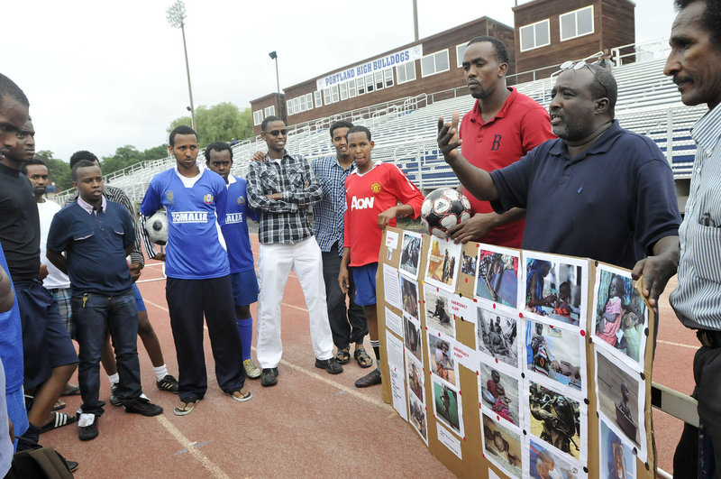 Mohamud Barre, executive director of the Somali Culture and Development Association of Maine, shows photographs from Somalia and speaks with soccer players prior to their games Friday.