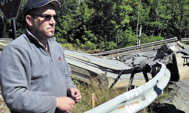 CLOSE CALL: Truck driver Yannick Livernoche of Quebec on Monday talks beside a collapsed bridge over the Carrabassett River on Route 27 in Carrabassett Valley.
