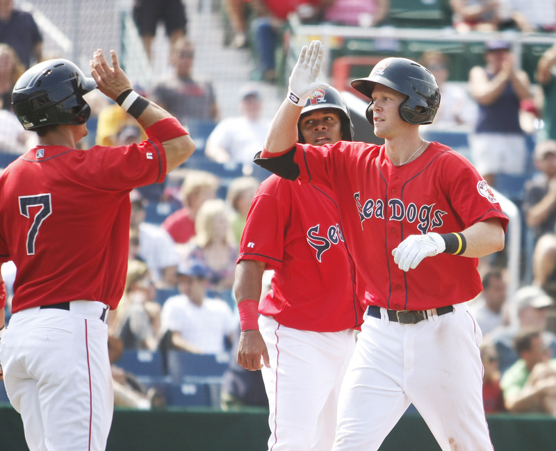 Jeremy Hazelbaker of the Sea Dogs is congratulated by Mark Wagner, left, and Ronald Bermudez after hitting a three-run homer in the fifth inning today against the Binghamton Mets at Hadlock Field. The Sea Dogs lost, 7-6.