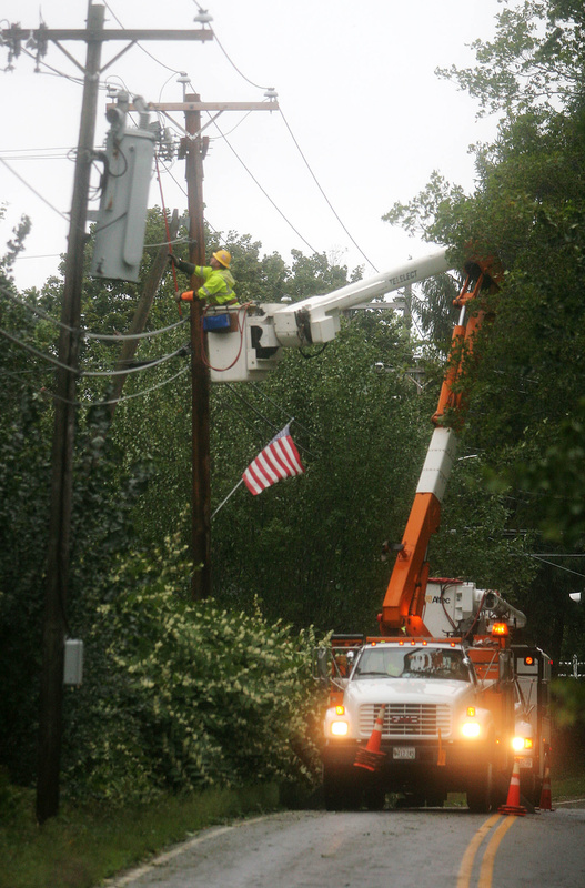 A Central Maine Power Co. lineman repairs lines pulled down by wind-blown trees and branches on Route 35 today.