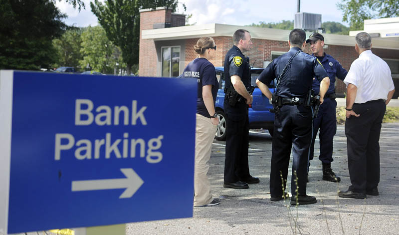 CASH AND CARRY: Police confer Monday in the parking lot of the Bangor Savings Bank branch on Capitol Street in Augusta. Police are investigating a report that a man demanded money from the bank and fled on foot shortly before 10:30 a.m. No weapon was displayed, according to police.