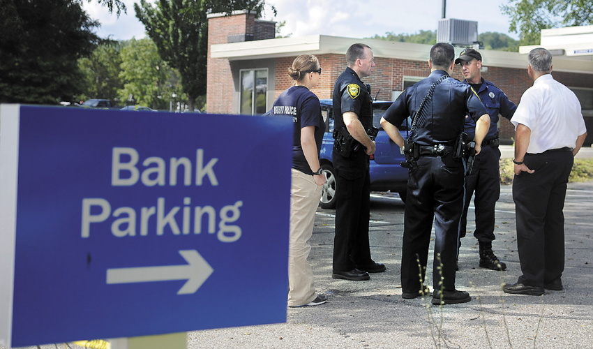 Staff photo by Andy Molloy Police confer in the parking lot Monday of the Bangor Savings Bank branch on Capitol Street in Augusta. Police are investigating a report that a man demanded money from the bank and fled on foot before 10:30 a.m. No weapon was displayed, according to police.
