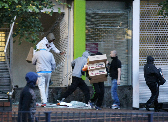 Looters take electrical goods after breaking into a store during the second night of civil disturbances in central Birmingham, England, on Tuesday.