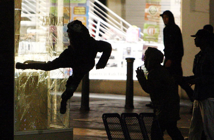 A youth kicks the window of a jewelry store near the Bullring shopping center in Birmingham, England, Monday evening.