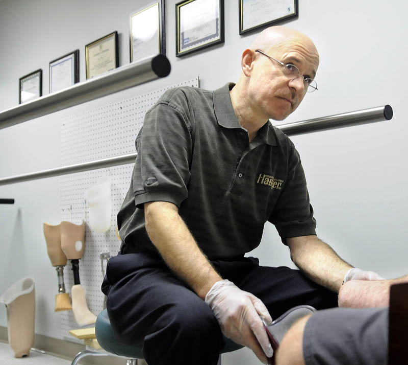 WORKS WITH THE INJURED: Kevin Carroll, left, assesses the amputated right leg of Pat Brown, of Pittsfield, Wednesday during a clinic at Hanger Prosthetics and Orthotics in Augusta. Brown lost his leg in a parachute accident.