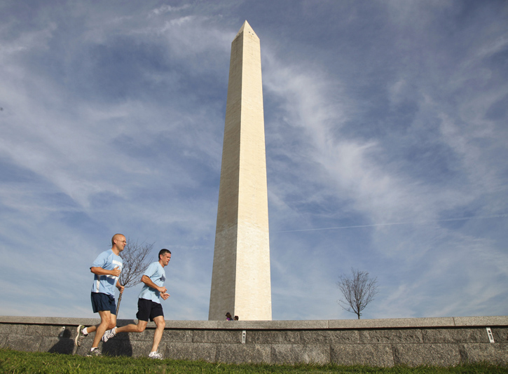 Joggers today run past the Washington Monument, which remains closed after a crack was discovered at the top of the towering white obelisk on The National Mall.