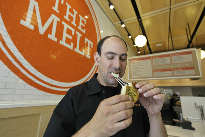 In this photo taken Aug. 25, 2011, Jonathan Kaplan bites into a melt called the Italian Job made with fontina and provolone cheese on garlic bread at The Melt in San Francisco.