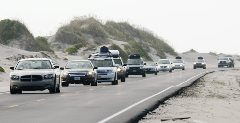 With a mandatory visitor evacuation in place, cars drive north on Highway 12 on Pea Island, N.C., in North Carolina's Outer Banks today.