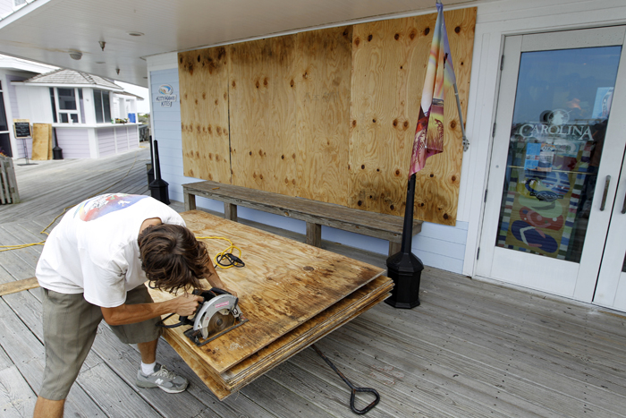 Jeremy Pickett cuts boards to protect the windows of a store in Cape Hatteras.