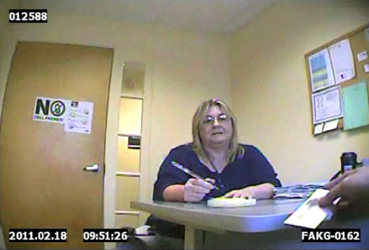 Screen capture from video of a Department of Health and Human Services worker talking with "Ted Ceanneidigh," not shown, a man trying to receive Medicaid benefits while broadly hinting that he is a drug smuggler.