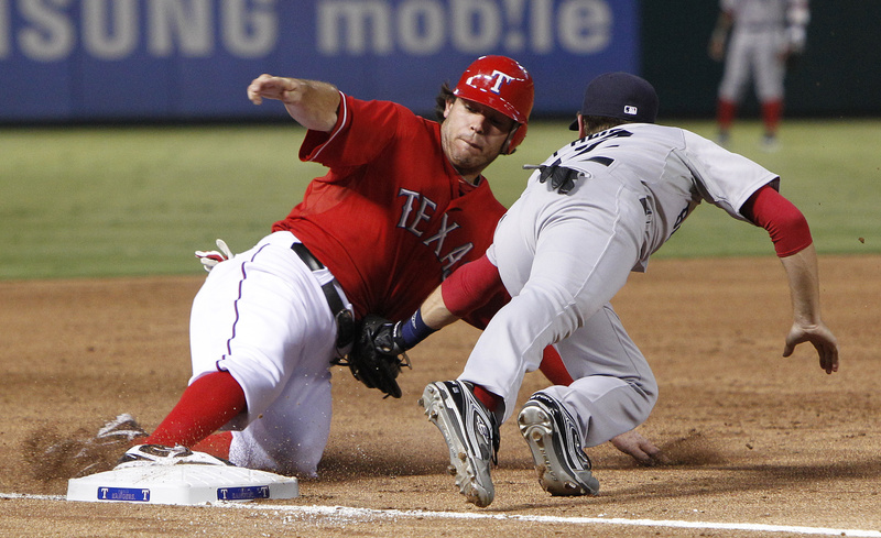 Texas Rangers' Ian Kinsler (5) beats the tag against Boston Red Sox third baseman Jed Lowrie (12) for the safe slide at third during the third inning of their game Monday in Arlington, Texas.
