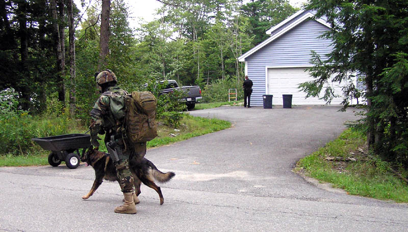 Staff photo by Scott Monroe A Maine State Police trooper runs by with a tracking dog on North Pond Road in Winslow Thursday afternoon where a man barricaded himself in a home and threatened to kill himself.