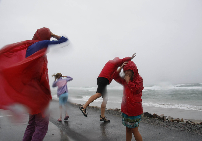 Kristen Day, far left, of Boston feels the powerful winds of Tropical Storm Irene with her family at Ogunquit Beach today while on vacation.