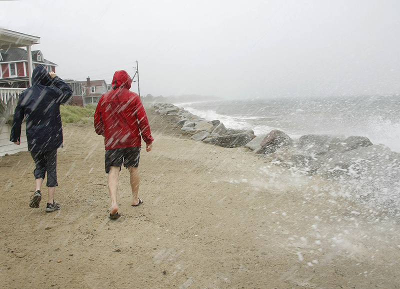 A couple walks along Surf Street in Saco as Tropical Storm Irene sends waves up over the rocks this morning.