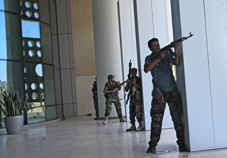 Rebel fighters take shelter as an intense gunbattle erupted outside the Corinthia hotel, where many foreign journalists are staying, in Tripoli today.