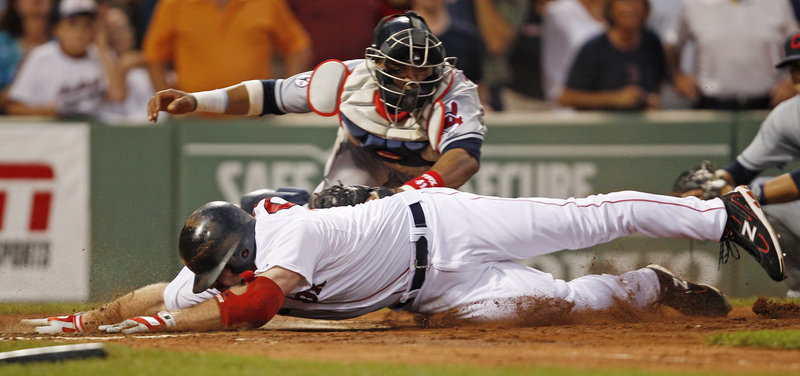 Indians catcher Carlos Santana tags out Boston’s Kevin Youkilis at the plate in the third inning Monday night. Youkilis was out trying to stretch his triple.