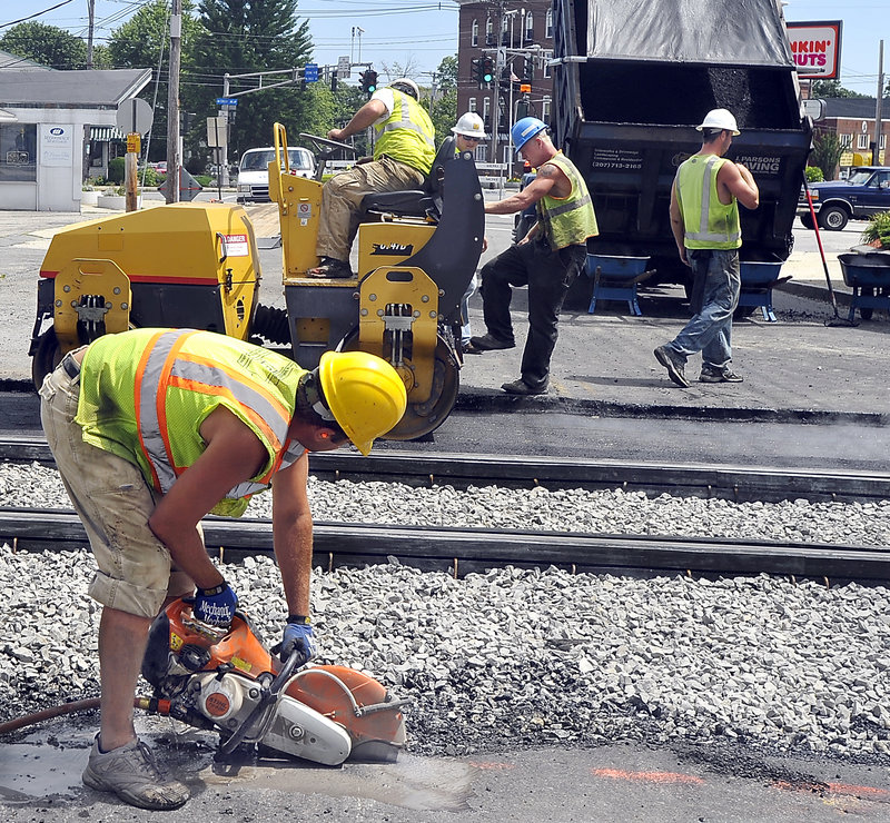 A.J. DeShon of J. Parsons Paving cuts pavement last week at Portland’s Woodfords Corner crossing, where new train tracks were laid as part of the Downeaster’s northern expansion.