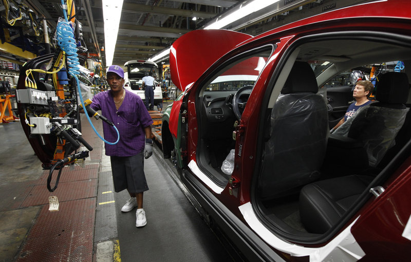 Assembly line worker Edward Houie moves a door into position for a 2012 Chevrolet Volt last month at GM’s assembly plant in Hamtramck, Mich. GM’s sales rose 7 percent in the second quarter to 2.3 million cars and trucks.