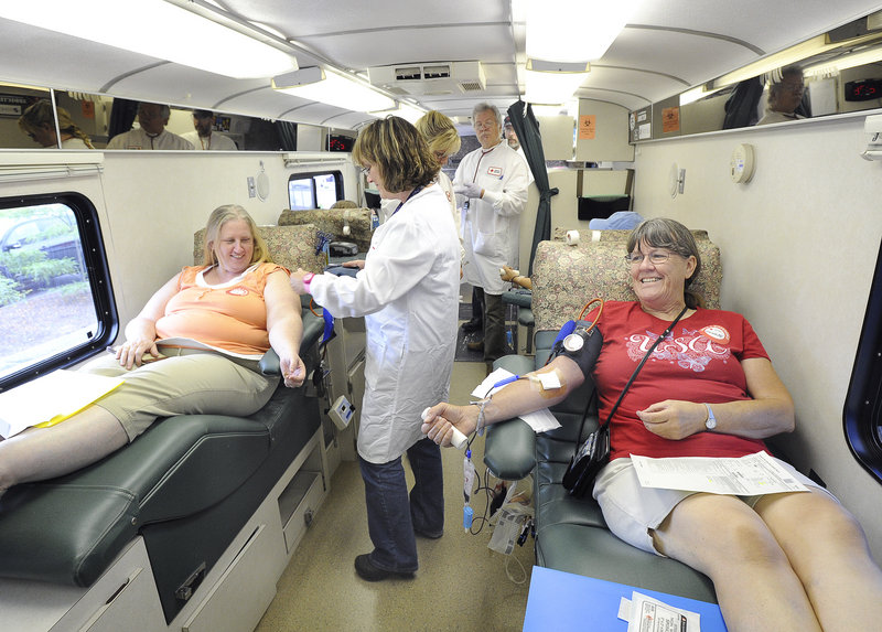 Collection technician Michelle Burnell assists Lori Crocker from Gorham as Bonnie Rooff relaxes beside them inside the Maine bus during the sixth annual marathon blood drive at the Cinemagic Stadium Theater in Westbrook.