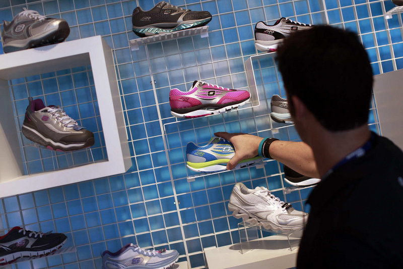 An employee adjusts a Skechers running shoe in a Manhattan Beach, Calif., store. The company is trying a lighter line.