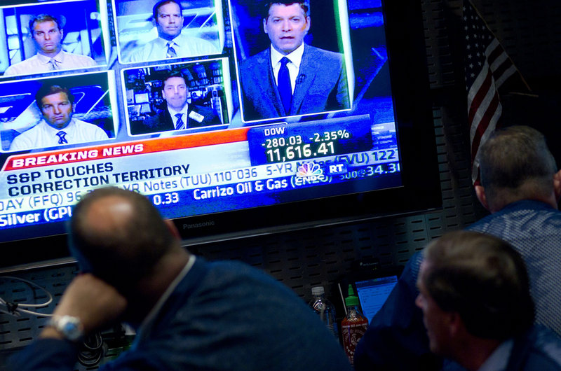 A monitor displays the plummeting Dow Jones Industrial Average and a host of news analysts and commentators weighing in as traders watch on the floor of the New York Stock Exchange on Thursday.