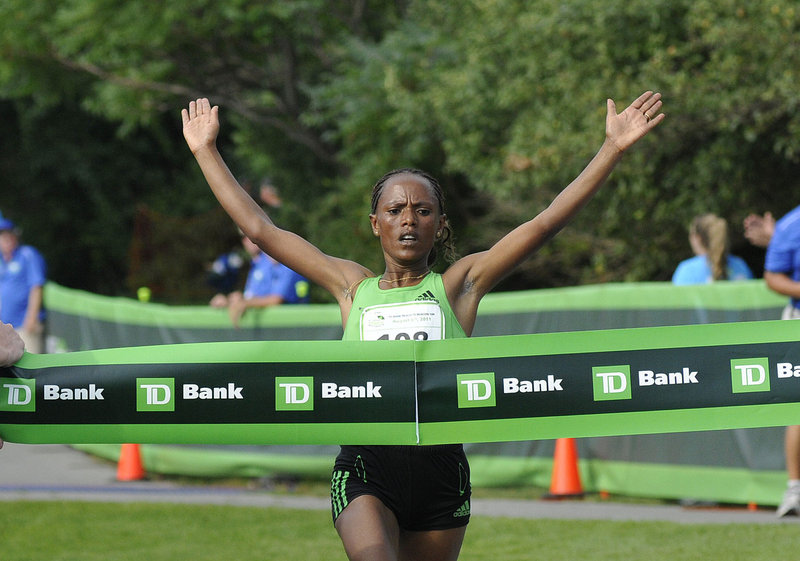 Aheza Kiros raises her arms as she crosses the finish line and captures the elite women's championship at the Beach to Beacon 10K road race on Saturday in Cape Elizabeth. Kiros survived on a hot day to finish in 32:08.7.