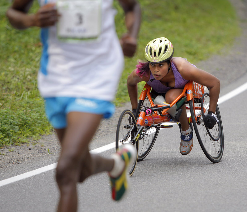 Christina Kouros, a Cape Elizabeth resident, pushes up a hill on Shore Road while being passed by runner Micah Kogo, the overall winner.