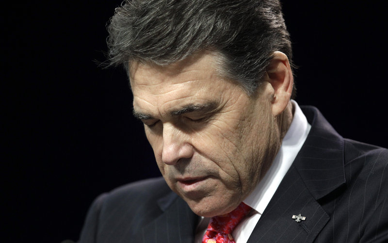 Texas Gov. Rick Perry bows his head as he leads a prayer Saturday in Houston.