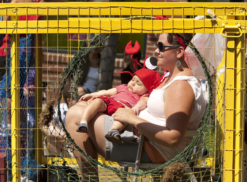 On a lobster-trap float during Saturday's parade, Rachel Winchenbach holds her 7-month-old daughter, Leandra, who remains blissfully unaware of the goings-on.