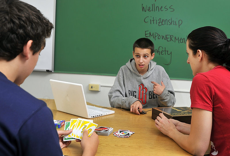 Kat Seevers, 15, center, talks with fellow student Garrett Ferland, 16, left, during a game of Uno. At right is Tamber Woodman, an educational technician.