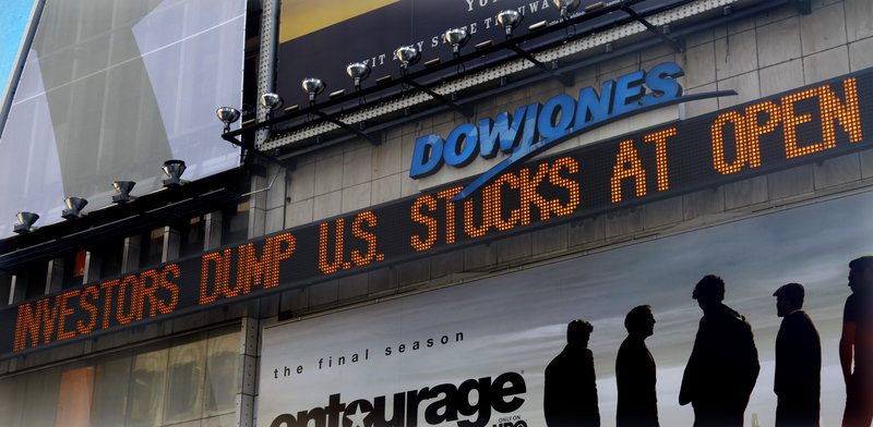 A Dow Jones news ticker in Times Square displays investor reaction Monday to a downgrade of the nation’s credit rating by Standard & Poor’s and the anemic economic recovery. Asian markets slumped again early today.